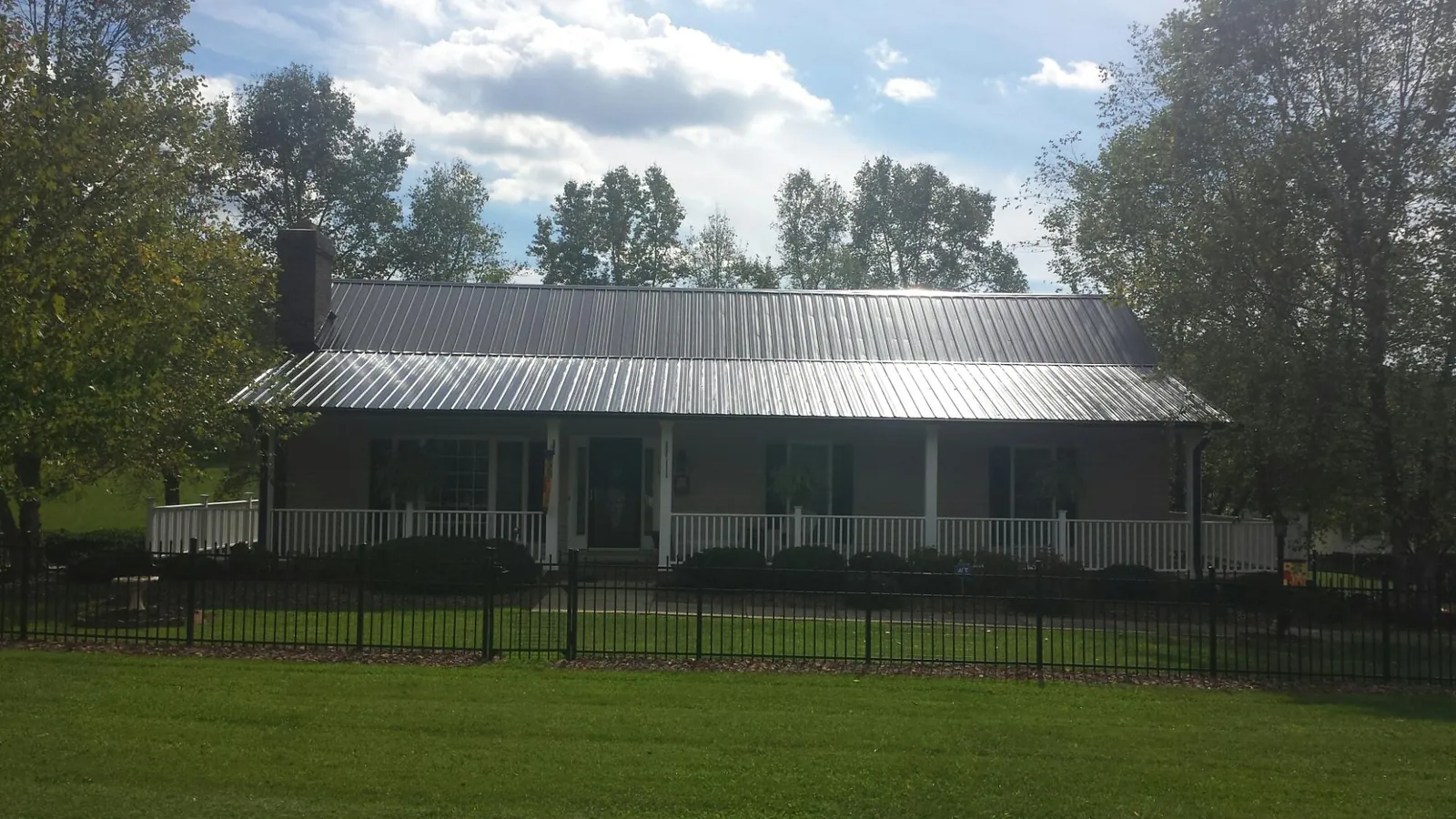Gray metal roof on a brick ranch with a full width front porch — Gutter Guard Installation work by our crew in Clifton
