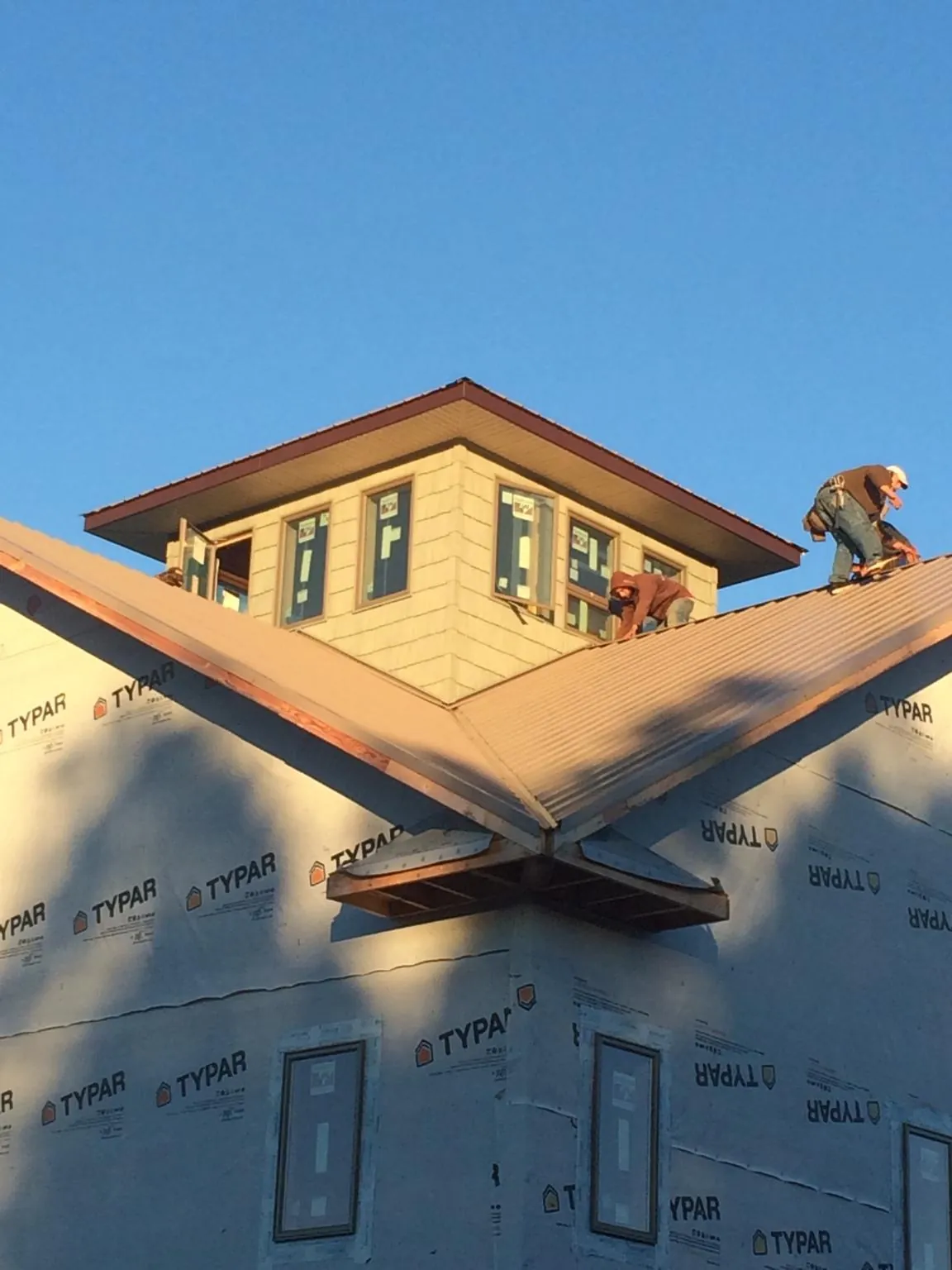 Roofers working around a rooftop cupola on a new metal roof at sunset — Roof Waterproofing in Clifton by Roofing Brothers